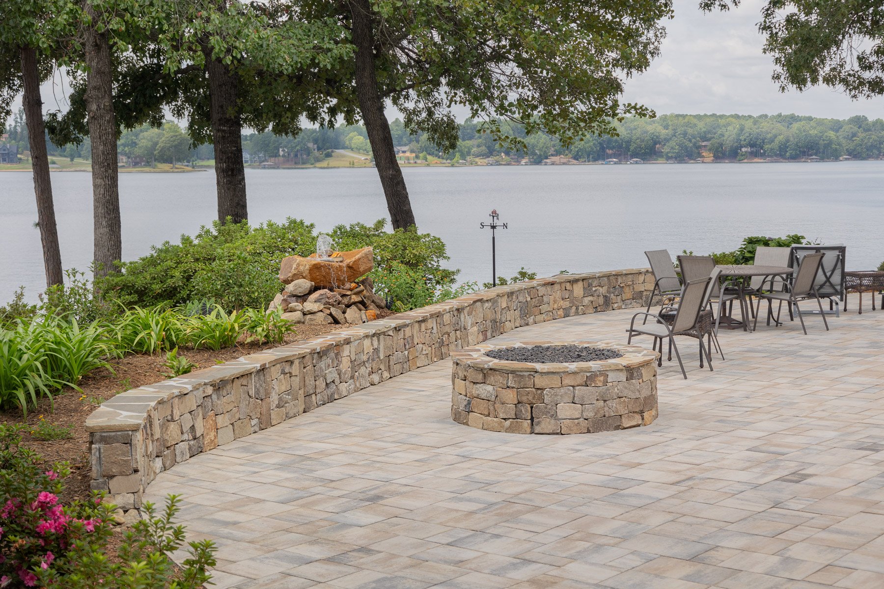 stone fire pit space on a patio with a water feature nearby