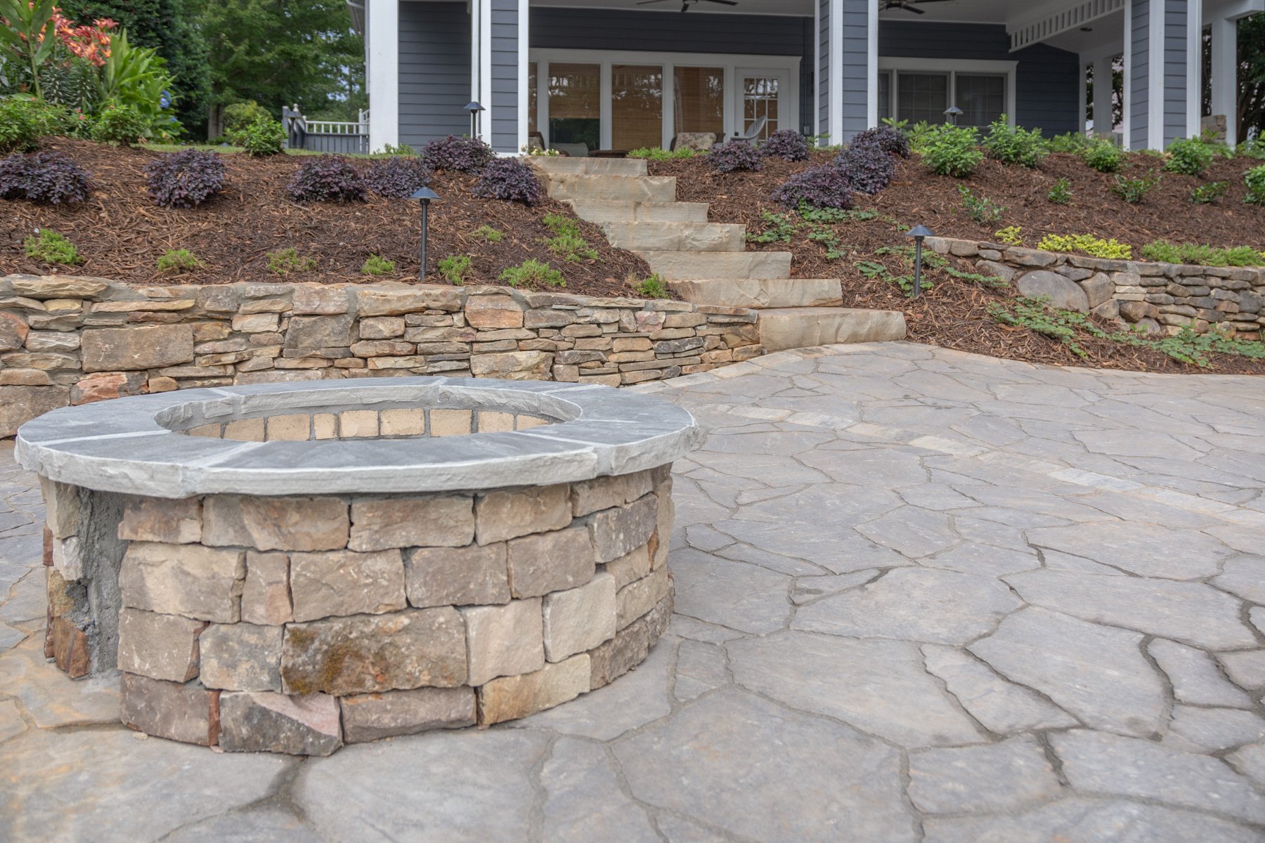 stone fire pit surrounded by raised planting beds to frame the space