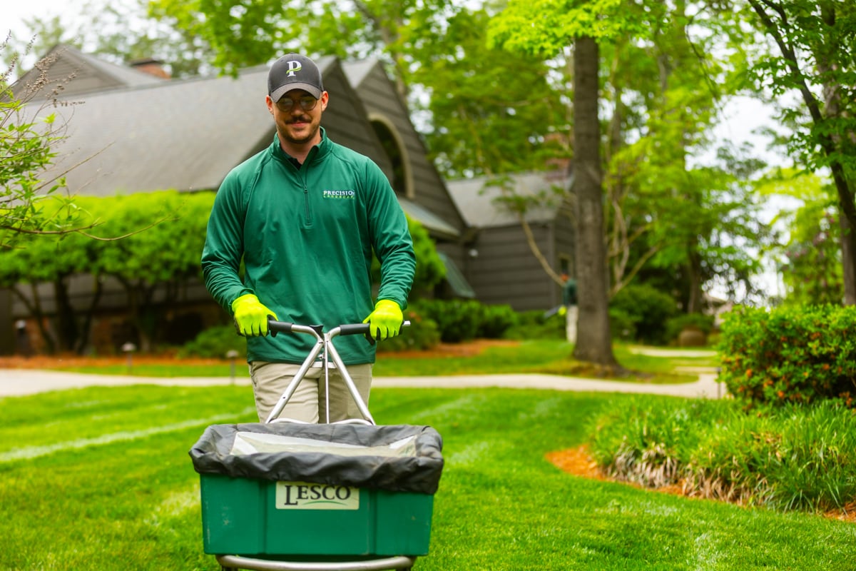 lawn care tech spreading granular fertilizer treatment grass yard happy