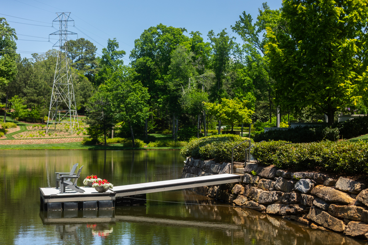 nice detail stone wall water lake dock ramp step rail shrubs seating potted flowers trees