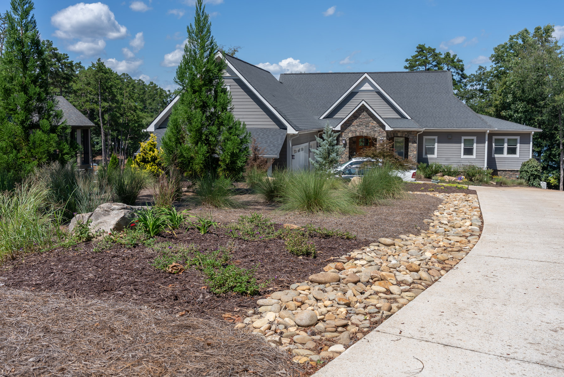 nice driveway entrance home grasses trees shrubs mulch gravel swale