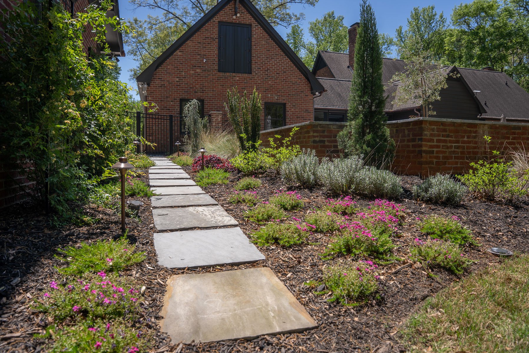 steppers flagstone flowers perennials light mulch home bed shrubs brick wall